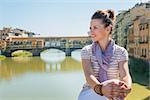 Remarkable holiday in Florence. Happy young tourist sitting on the bridge overlooking Ponte Vecchio and looking into the distance