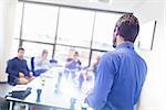 Business man making a presentation at office. Business executive delivering a presentation to his colleagues during meeting or in-house business training, explaining business plans to his employees.