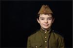 Portrait of young boy in Soviet military uniform on black background