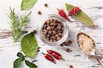 Traditional spice and condiment on white wooden background. Bay leaves, rosemary, chillies and black pepper on wooden table, top view.