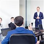 Colleague asking a question to  businessman during a presentation. Successful team leader and business owner  leading informal in-house business meeting. Business and entrepreneurship concept.