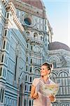 An amble around awe-inspiring Duomo in Florence, Italy. Happy woman tourist with map looking on something while standing in the front of Duomo