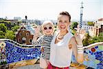 Barcelona will show you how to remarkably spend holiday. Smiling mother and baby at Park Guell handwaving