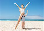 Family fun on white sand. Happy mother and child in swimsuits at sandy beach on a sunny day rejoicing