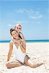 Family fun on white sand. Portrait of happy mother and child in swimsuits at sandy beach on a sunny day