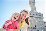 Family discovering old Italian treasures in Florence. Portrait of cheerful mother and child near Palazzo Vecchio