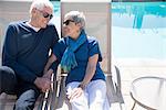 Senior couple relaxing on sun loungers beside pool