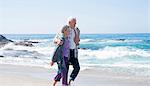 Senior couple walking along beach, smiling