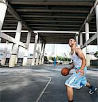 Young man on basketball court holding basketball looking up smiling