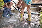 Children playing with water hose on sidewalk