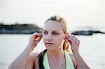 Woman inserting earbuds looking away