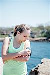 Woman wearing earbuds looking at activity tracker on arm