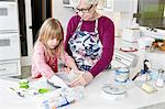 Girl and grandmother preparing greaseproof paper in baking tray