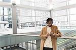 Young businessman selecting smartphone music in train station