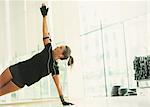 Woman balancing in side plank in gym studio