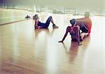 Friends resting and talking on gym studio floor