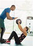 Personal trainer guiding woman with medicine ball at gym