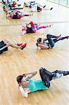 Exercise class doing bicycle sit-ups at gym