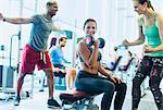 Woman cheering on friend doing dumbbell biceps curls at gym