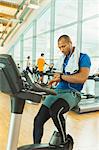 Man checking smart watch on exercise bike at gym