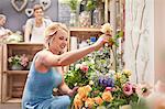 Smiling woman picking out flowers in flower shop