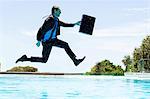 Businessman jumping in the swimming pool