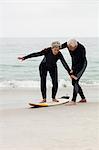 Senior man teaching woman to surf