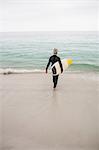 Rear view of senior woman walking towards sea