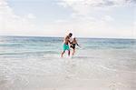 Senior couple holding hands and running on the beach