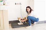 Happy woman weighing her dog on a veterinary scales