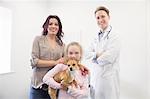 Mother, daughter and vet standing with dog