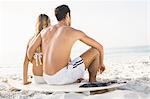 Happy couple sitting on surfboard