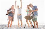 Cute group of friends having a barbecue and beers and playing the guitar