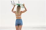 Pretty blonde woman holding a surfboard over her head
