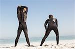 Handsome men stretching in wetsuits