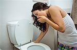 Young woman about to vomit into a commode toilet