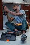 Manual worker drilling a hole in kitchen