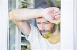 Depressed man leaning his head on window glass