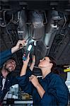 Mechanics examining car using flashlight