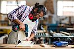 Carpenter drilling a hole in a wooden plank