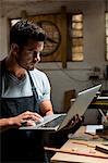 Carpenter using laptop in workshop