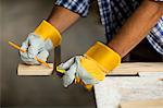 Carpenter marking on wooden plank with pencil