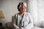 Thoughtful businesswoman sitting on her bed