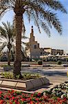 Palm trees and flower beds along Al-Corniche, waterfront promenade, with Qatar Islamic Cultural Centre, Doha, Qatar, Middle East