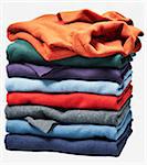 Stack of different coloured sweaters on white background