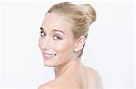 Rear view of woman with hair bun looking over bare shoulder at camera smiling