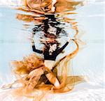 Woman in black posing underwater in pool