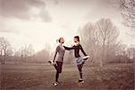 Full length side view of women face to face on one leg, hands on each others shoulders