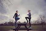 Full length side view of women doing step ups on picnic bench