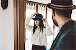 Young man waiting for woman trying on hat